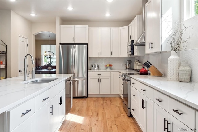 1026 Deer Clover Way, Castle Pines, CO 80108 - kitchen with stainless steel appliances, a sink, light wood finished floors, white cabinets, and light stone countertops