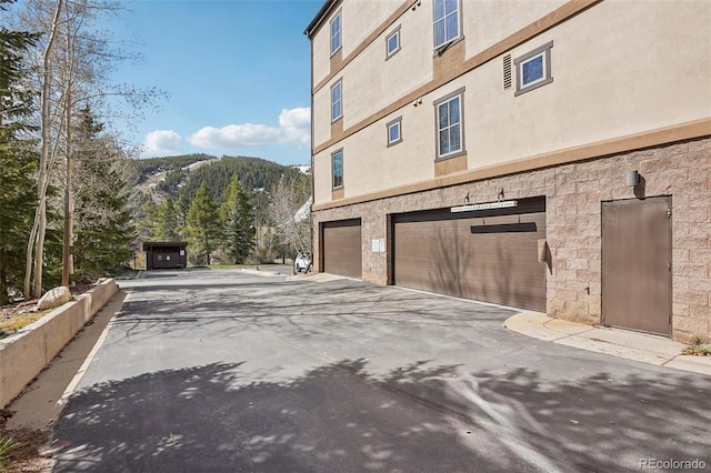 22787 US Highway 6 Unit 302, Keystone, CO 80435 - view of side of home featuring an attached garage, driveway, stucco siding, and a mountain view