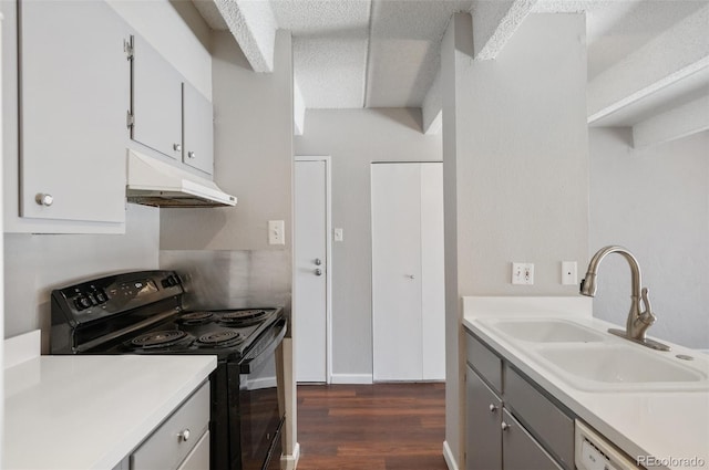 kitchen featuring dark wood-style flooring, black / electric stove, light countertops, under cabinet range hood, and a sink