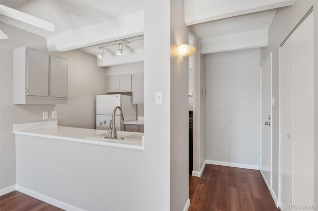 kitchen featuring baseboards, light countertops, dark wood-type flooring, and freestanding refrigerator