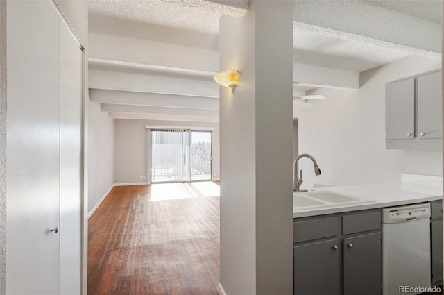 kitchen featuring light countertops, gray cabinets, white dishwasher, and a sink