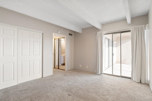 unfurnished bedroom featuring light carpet, access to outside, a textured ceiling, and beamed ceiling