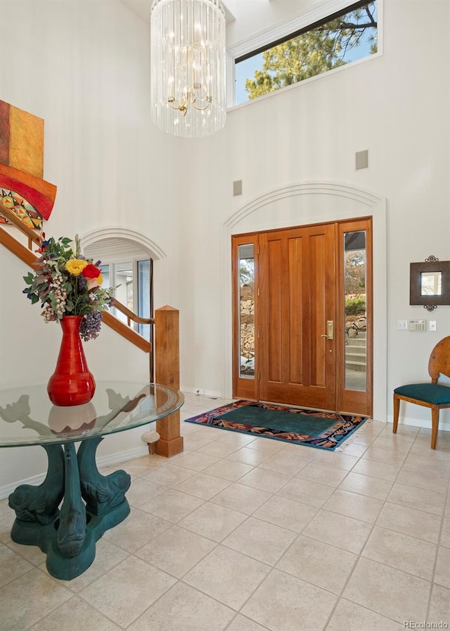 foyer featuring light tile patterned floors, a chandelier, and a high ceiling