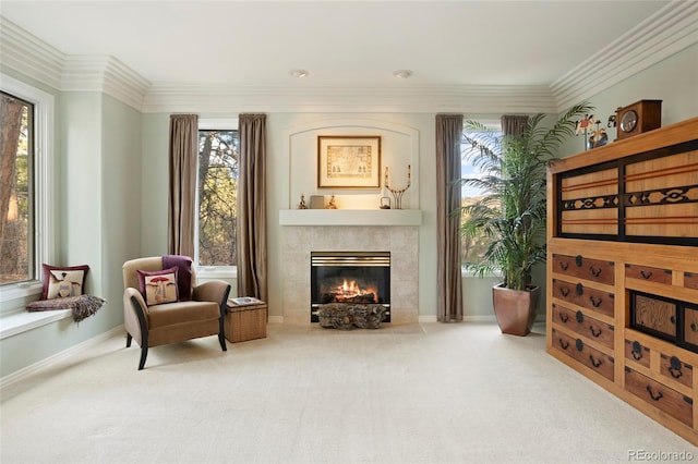 living area with a tile fireplace, crown molding, carpet, and a healthy amount of sunlight