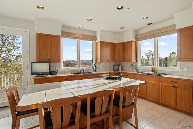 kitchen with tasteful backsplash, stainless steel appliances, sink, a center island, and tile counters