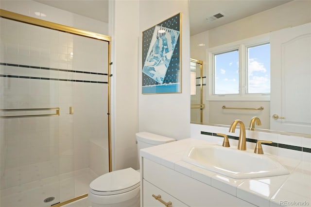 bathroom featuring vanity, toilet, and a shower with shower door