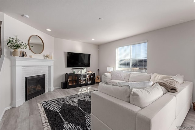 living room featuring a brick fireplace and light wood-type flooring