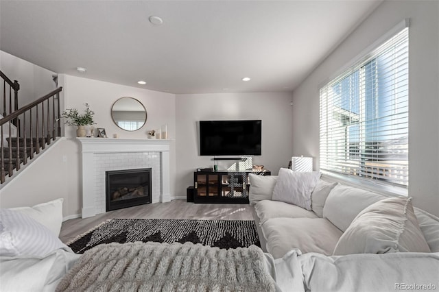 living room with a brick fireplace and light hardwood / wood-style flooring