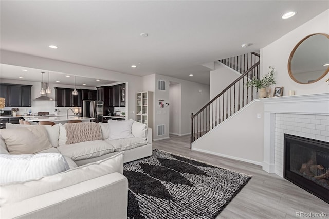 living room with sink, a fireplace, and light hardwood / wood-style floors