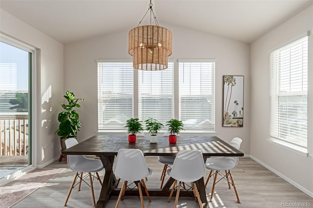 dining room featuring lofted ceiling, light hardwood / wood-style flooring, and a notable chandelier