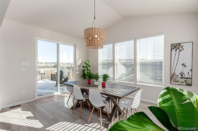 dining room featuring lofted ceiling, a healthy amount of sunlight, and light wood-type flooring