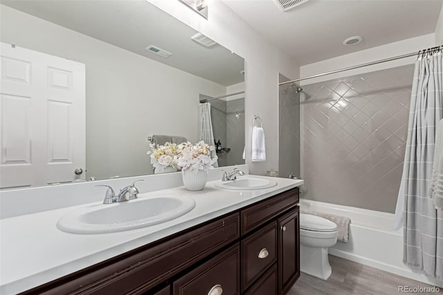 full bathroom featuring hardwood / wood-style flooring, vanity, toilet, and shower / tub combo