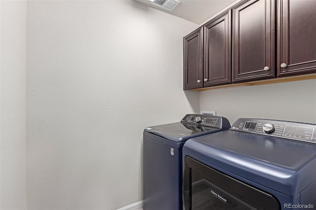 clothes washing area featuring cabinets and independent washer and dryer