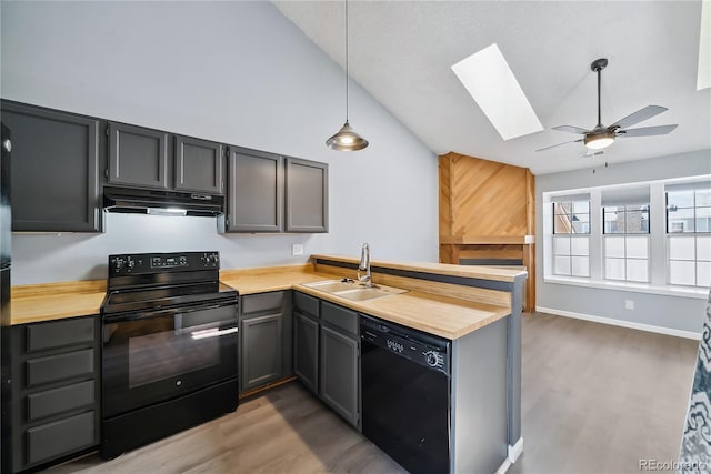 kitchen featuring sink, lofted ceiling with skylight, pendant lighting, wood-type flooring, and black appliances