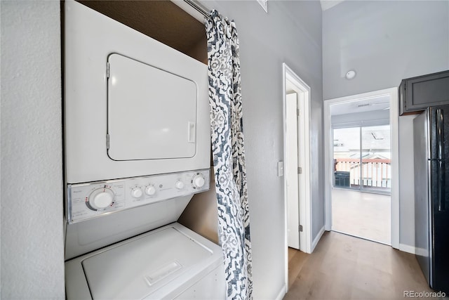 washroom with light wood-type flooring and stacked washer / dryer