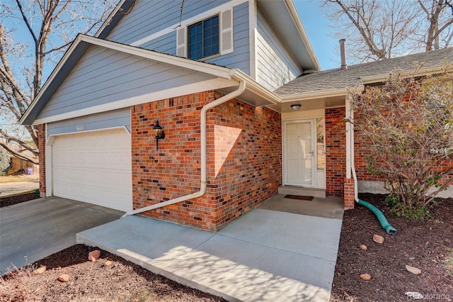 doorway to property featuring brick siding, concrete driveway, a garage, and a shingled roof