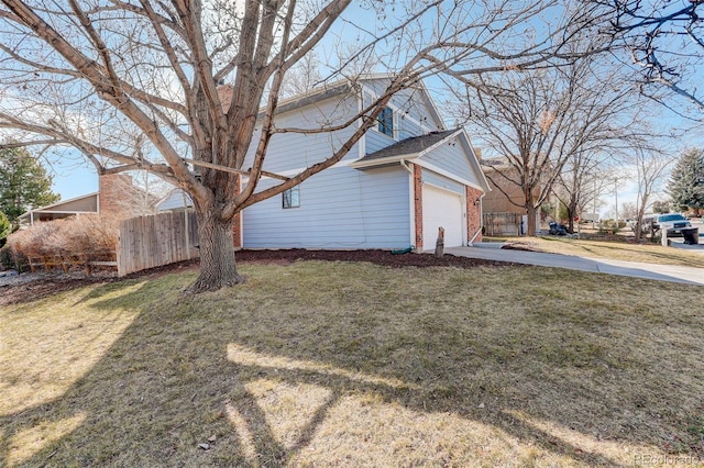 view of home's exterior featuring brick siding, a lawn, concrete driveway, and fence