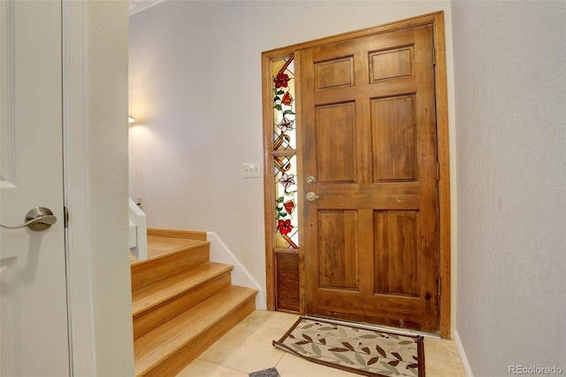 foyer entrance with light tile patterned flooring and stairs