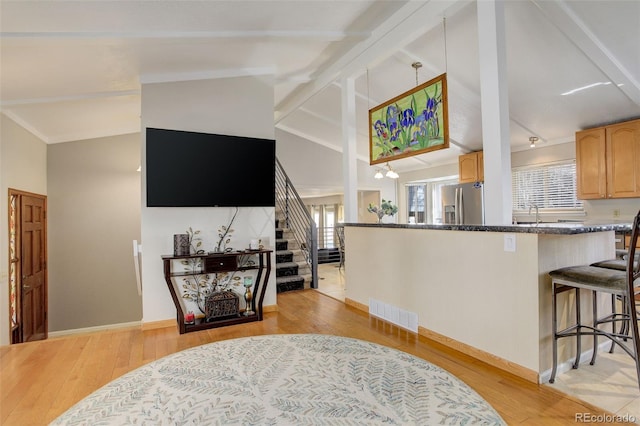 kitchen featuring lofted ceiling, light wood-style flooring, stainless steel fridge with ice dispenser, and visible vents