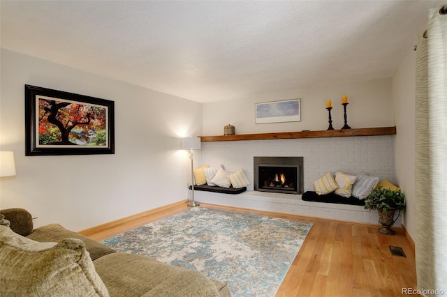 living area with wood finished floors, a fireplace, baseboards, and visible vents