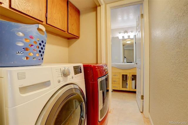 laundry area featuring washing machine and dryer, cabinet space, a textured wall, and a sink