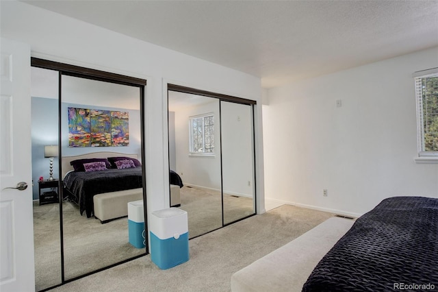 carpeted bedroom featuring visible vents, baseboards, and two closets