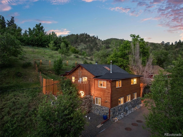 2874 SE Grapevine Rd, Idledale, CO 80453 - view of home's exterior featuring a forest view, stone siding, and a shingled roof