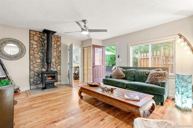 2874 SE Grapevine Rd, Idledale, CO 80453 - living area with a ceiling fan, a wood stove, wood finished floors, and a textured ceiling
