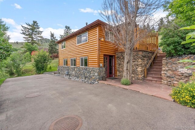 2874 SE Grapevine Rd, Idledale, CO 80453 - chalet / cabin with stone siding, faux log siding, a patio, and stairway
