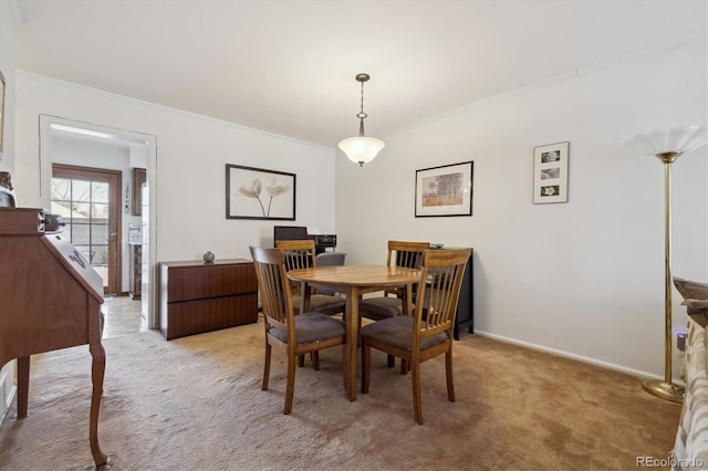 dining space featuring baseboards, ornamental molding, and light colored carpet