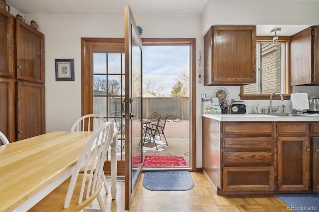 kitchen featuring brown cabinets, plenty of natural light, light countertops, and a sink