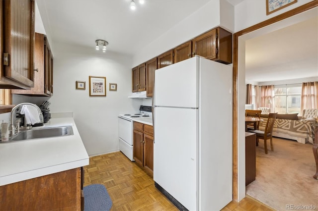 kitchen featuring light countertops, white appliances, brown cabinetry, and a sink