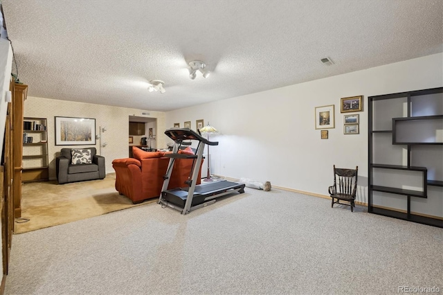 exercise area with light carpet, visible vents, baseboards, and a textured ceiling