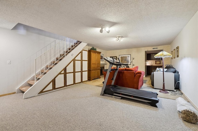 exercise room featuring a textured ceiling, carpet flooring, and baseboards