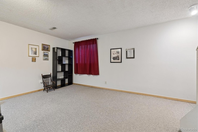 carpeted empty room featuring a textured ceiling, visible vents, and baseboards