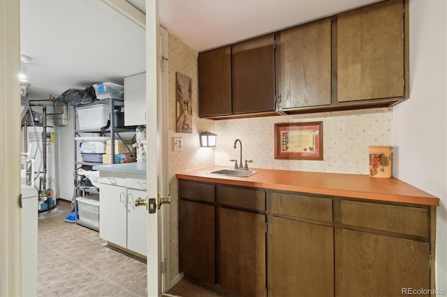 kitchen with light floors, a sink, light countertops, and wallpapered walls