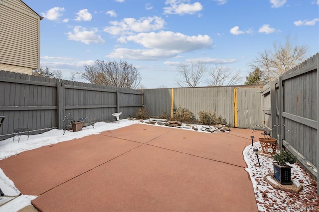 snow covered patio featuring a fenced backyard