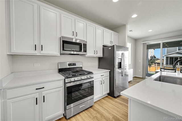 4644 Hatcher Dr, Brighton, CO 80601 - kitchen with stainless steel appliances, light wood-style flooring, white cabinets, recessed lighting, and light countertops