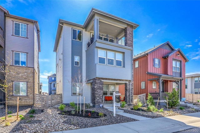 8728 Hotchkiss St, Littleton, CO 80125 - view of front of home with a balcony, fence, and stone siding