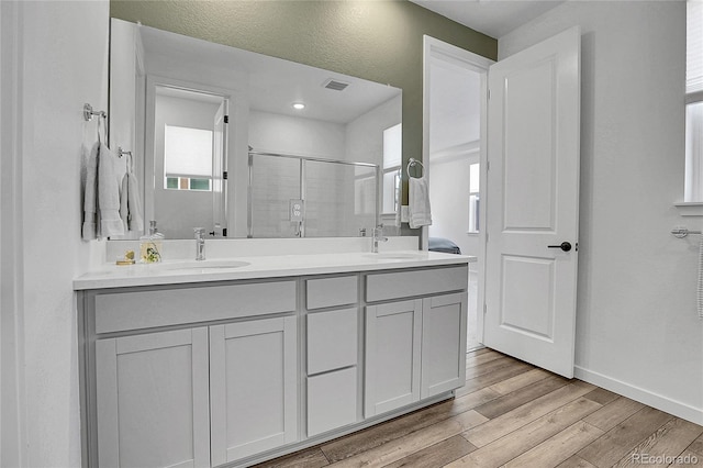 8728 Hotchkiss St, Littleton, CO 80125 - bathroom with a stall shower, wood finished floors, double vanity, and baseboards