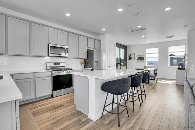 8728 Hotchkiss St, Littleton, CO 80125 - kitchen with stainless steel appliances, gray cabinetry, a center island, light countertops, and tasteful backsplash