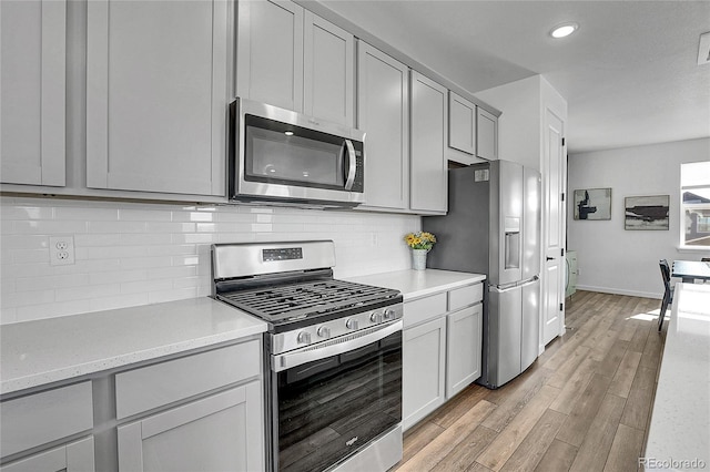 8728 Hotchkiss St, Littleton, CO 80125 - kitchen featuring stainless steel appliances, gray cabinets, light countertops, light wood-style floors, and tasteful backsplash