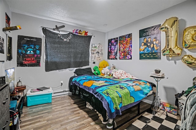 bedroom featuring a baseboard radiator, hardwood / wood-style floors, and a textured ceiling