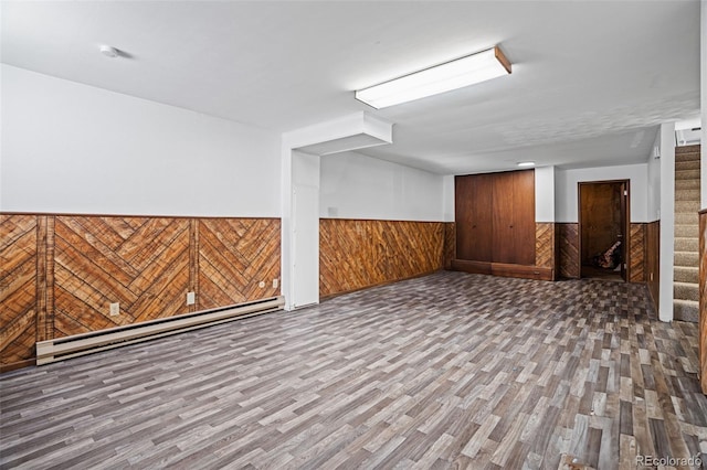 basement featuring hardwood / wood-style flooring, a baseboard heating unit, and wooden walls