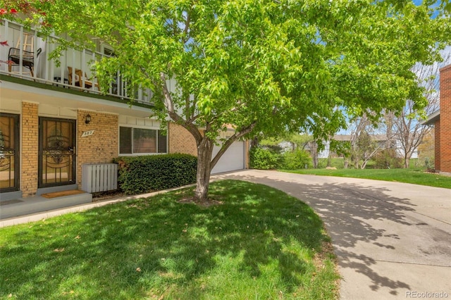 387 Upham St, Lakewood, CO 80226 - view of front facade with concrete driveway, brick siding, a garage, and a front yard