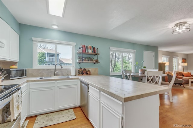 387 Upham St, Lakewood, CO 80226 - kitchen featuring a sink, a peninsula, appliances with stainless steel finishes, and light wood-type flooring
