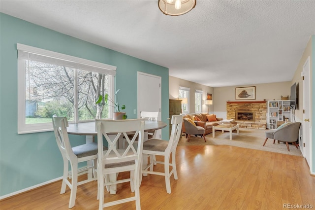 387 Upham St, Lakewood, CO 80226 - dining area featuring a fireplace, wood finished floors, a textured ceiling, and baseboards