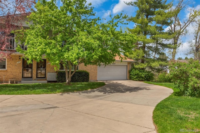 387 Upham St, Lakewood, CO 80226 - obstructed view of property featuring brick siding, concrete driveway, an attached garage, and a front yard