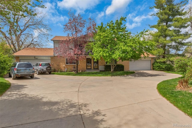 387 Upham St, Lakewood, CO 80226 - view of property hidden behind natural elements with concrete driveway, an attached garage, and brick siding