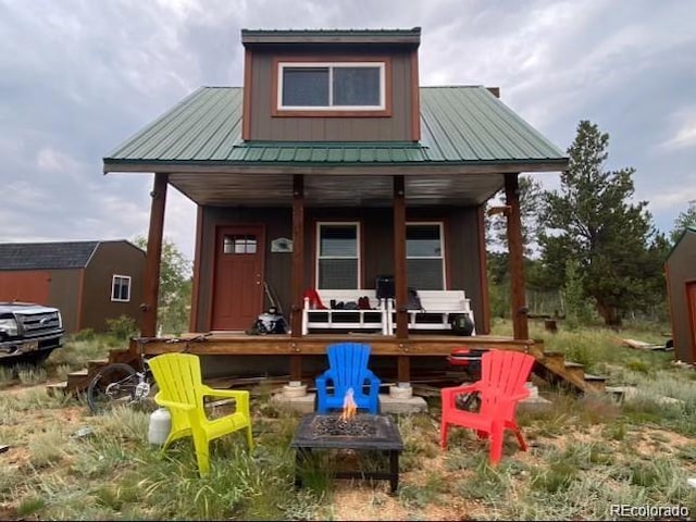 view of front facade with a storage shed, a porch, and an outdoor fire pit